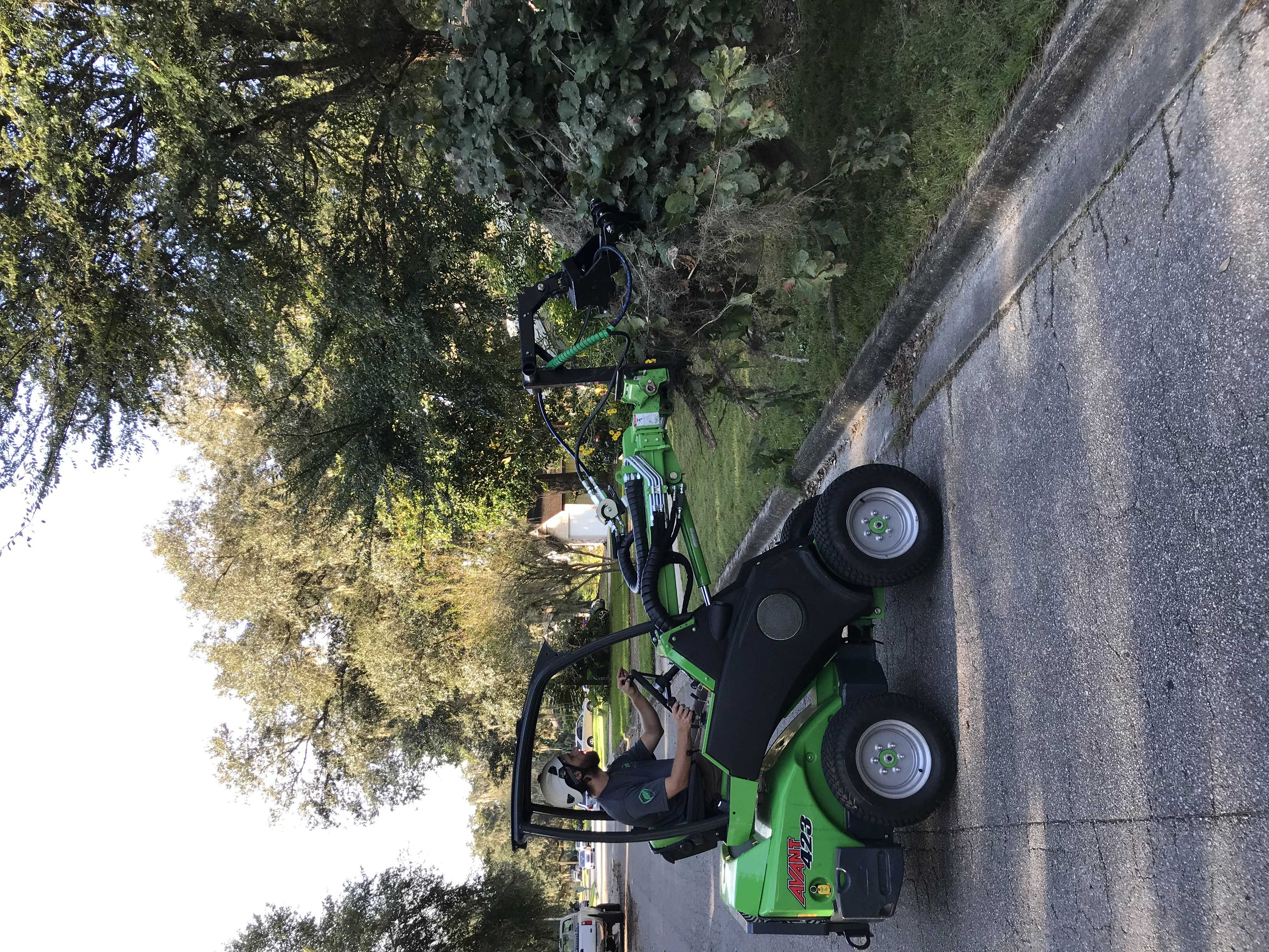 An Avant wheel loader lifting a large pile of brush off of a lawn.